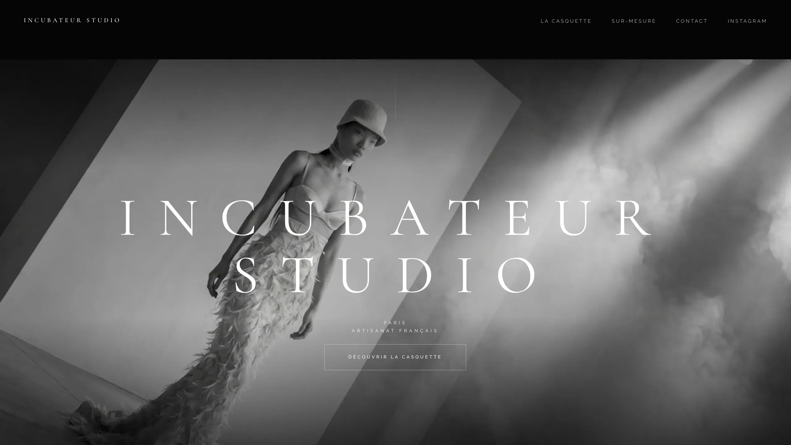 Page d'accueil du site Incubateur Studio — mannequin en robe couture et casquette, noir et blanc cinématique